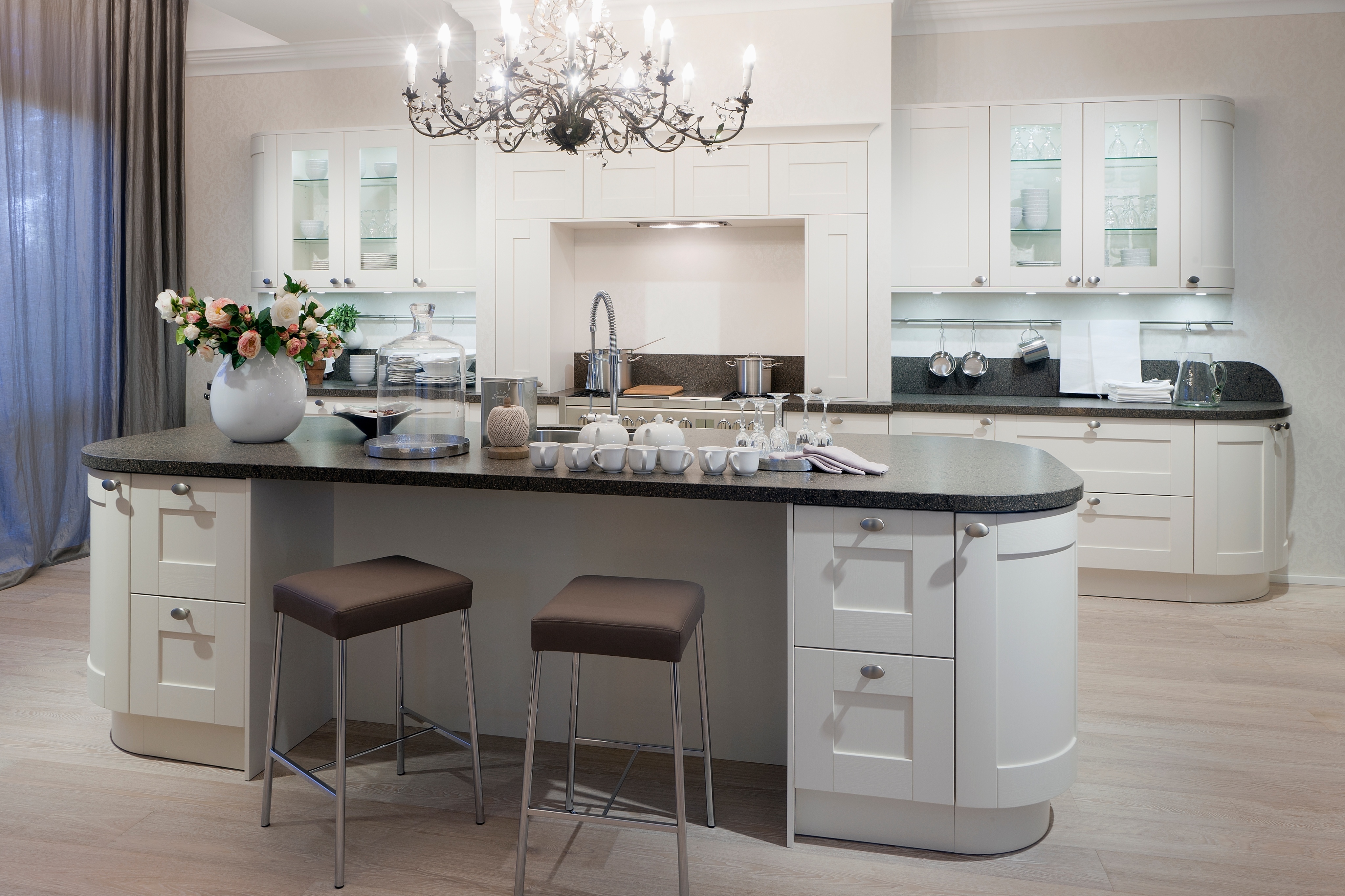 weiße Küche mit Arcardenschränken, Silberknaufen und dazu passendem Kronleuchter