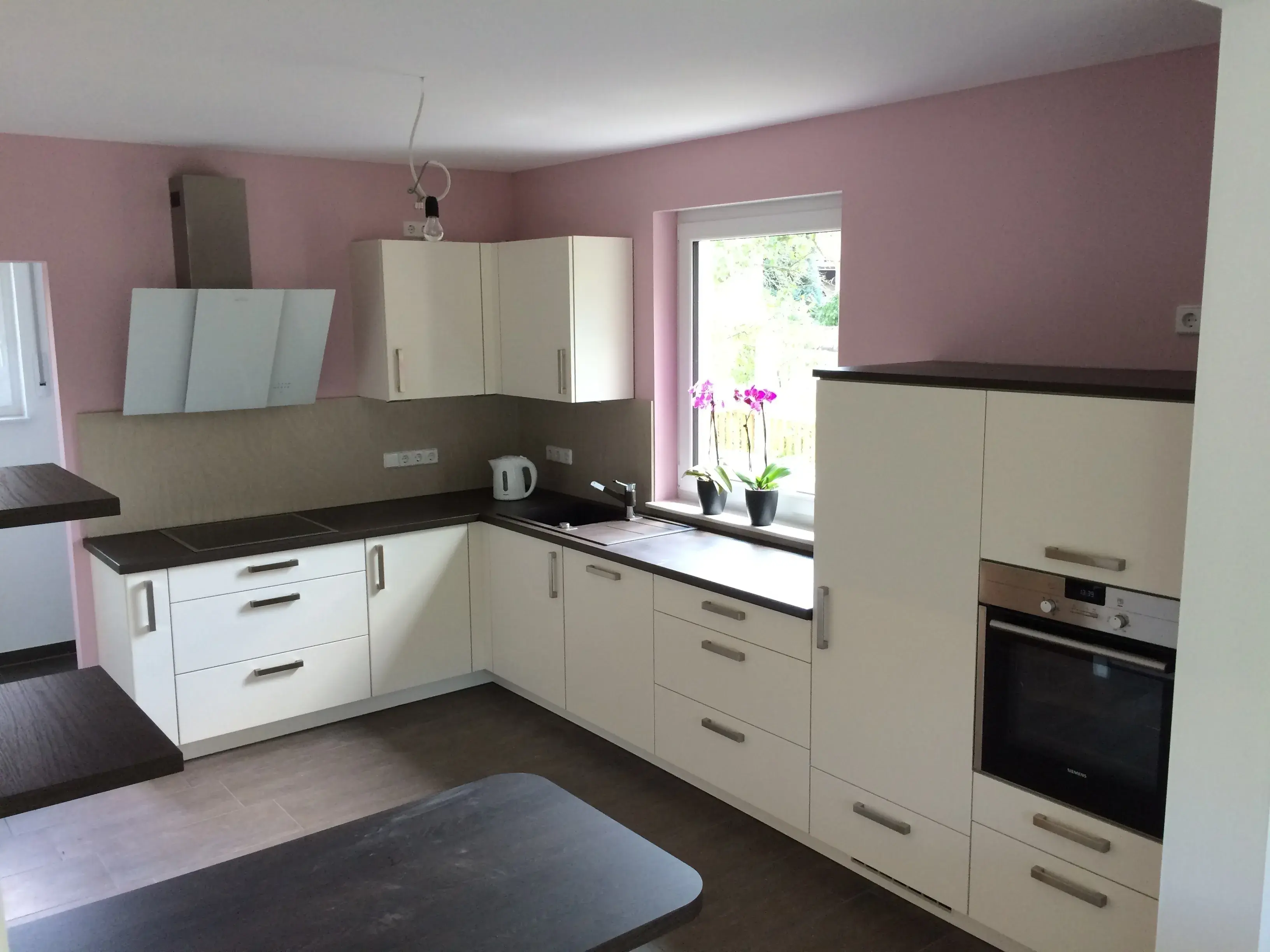 moderne Küche mit Schräghaube, Hängeschränke, hochgesetzter Backofen, weiße Fronten