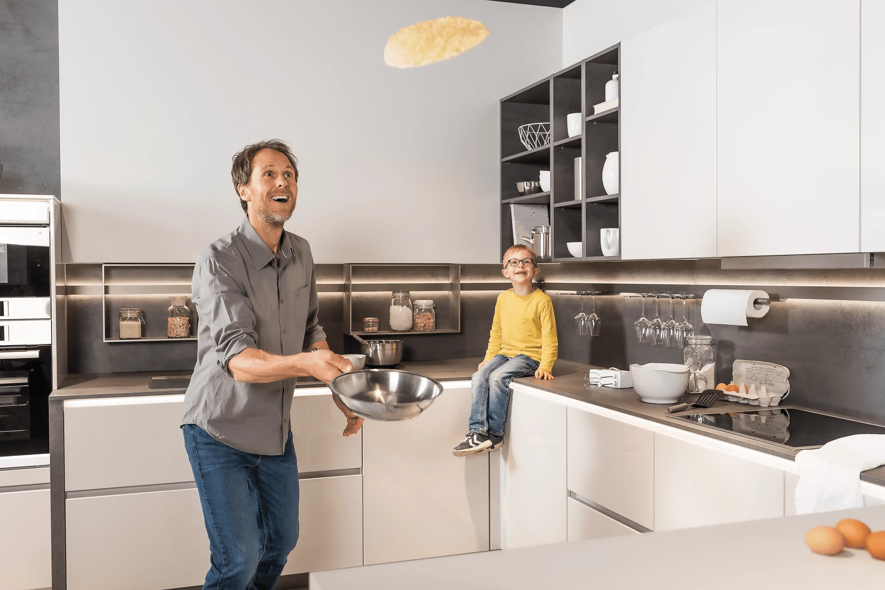 Werbemotiv für GK - Gute Küchen _Vater wendet Pfannkuchen für Sohn